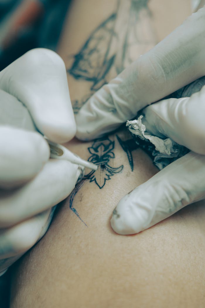 Detailed view of tattoo artist creating intricate design on skin using precision tools.