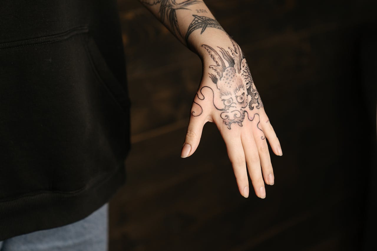 Close-up of a person's hand with a detailed dragon tattoo in black ink, showcasing intricate body art.